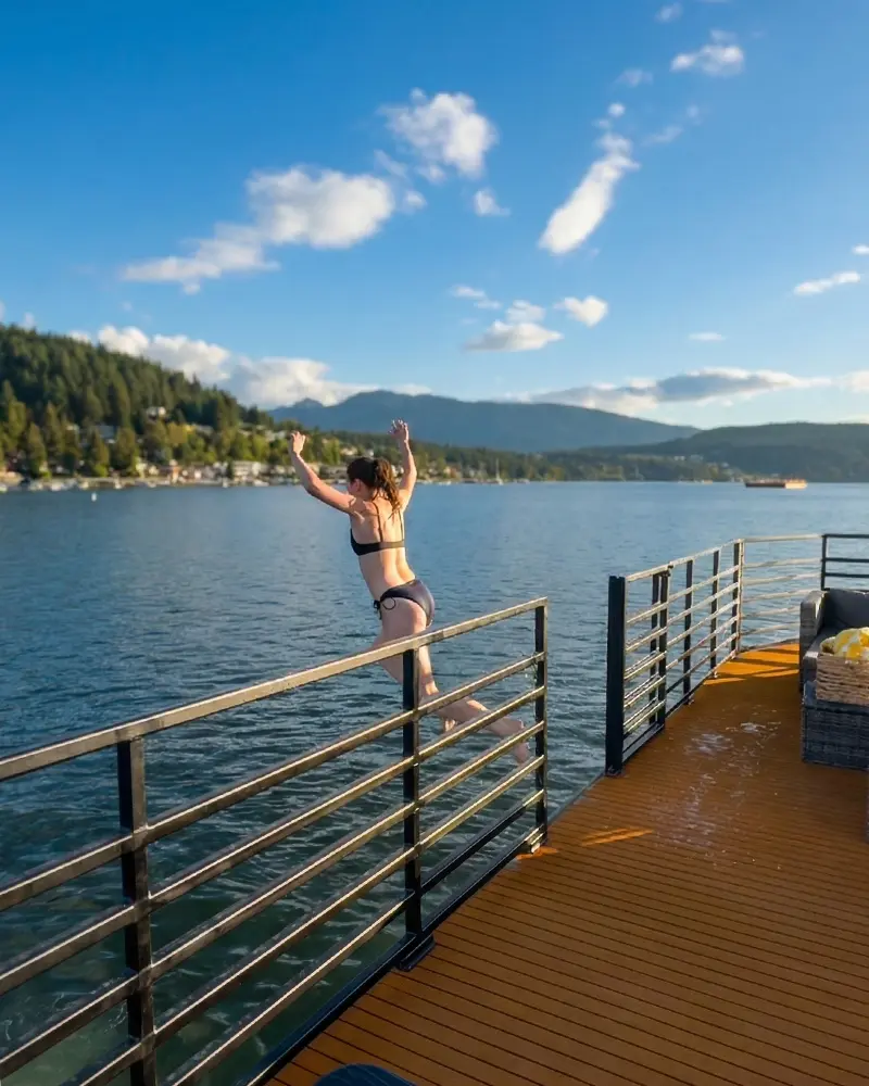 A guest jumping from the railing of the sauna boat into the cold ocean water for a polar plunge experience in Deep Cove.