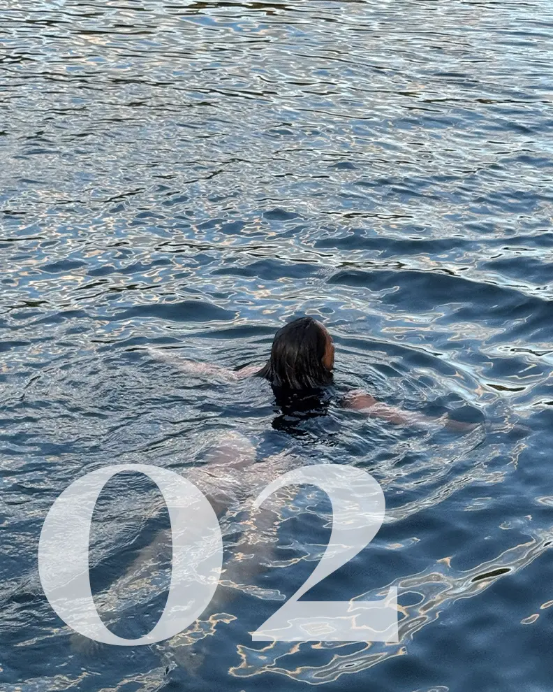 A guest swimming in the emerald glacial waters of Indian Arm fjord during a Hot Voyage sauna boat experience.