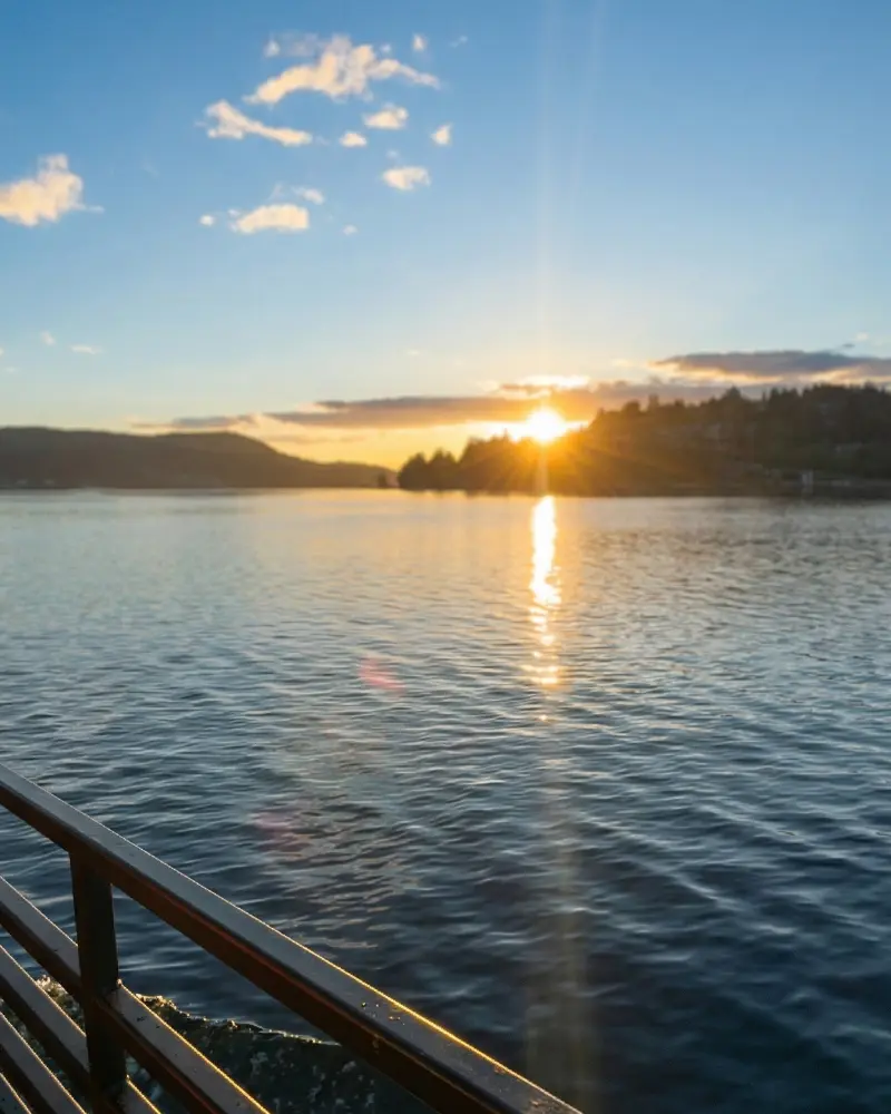 Golden hour sunset view over the water seen from the deck railing of a private boat charter in Port Moody.