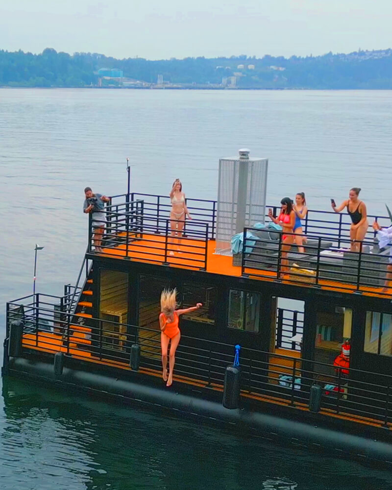 Guests standing on the outdoor decks of the Hot Voyage sauna boat.