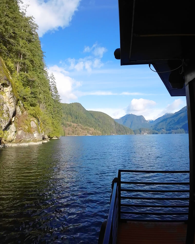 View from the deck of a sauna boat approaching a large coastal waterfall.