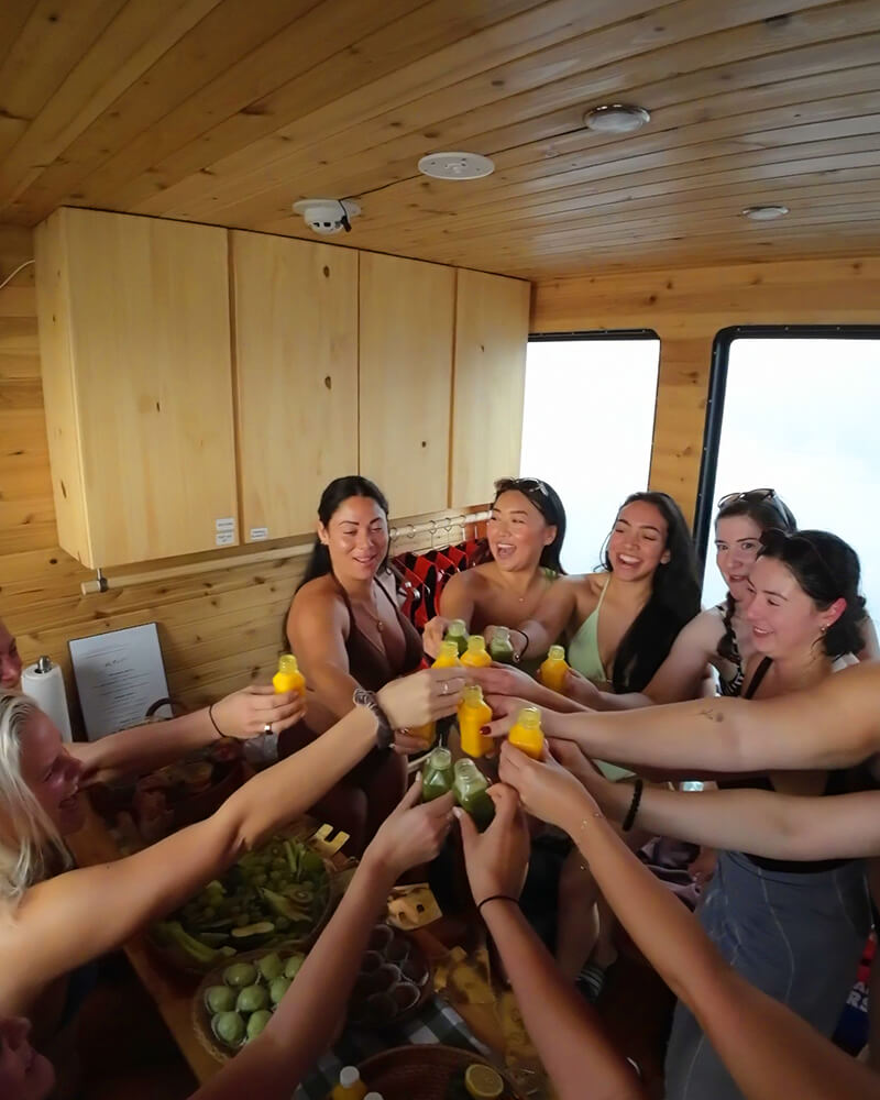 Group of women cheering with drinks inside the Hot Voyage sauna boat.