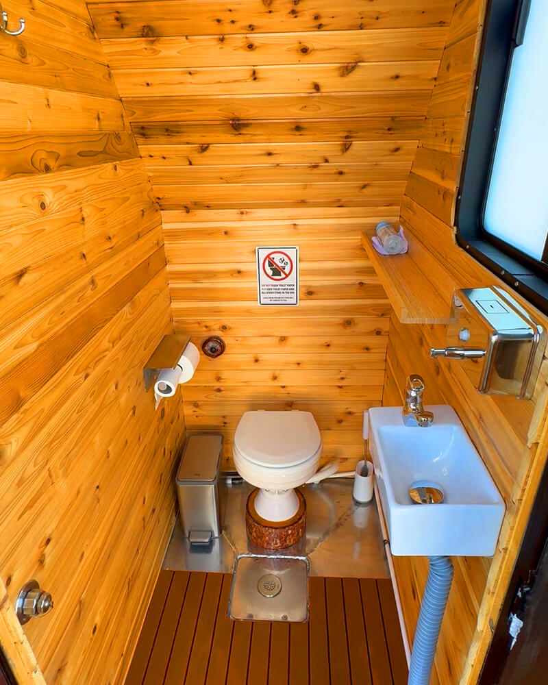 Clean, private onboard washroom with a toilet inside the Hot Voyage sauna boat.