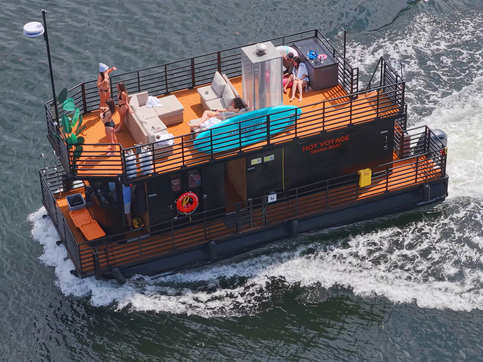 Aerial view of the Hot Voyage sauna boat cruising with guests relaxing on the rooftop lounge