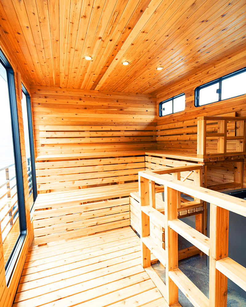 Multi-level wooden cedar benches inside the Hot Voyage sauna boat.