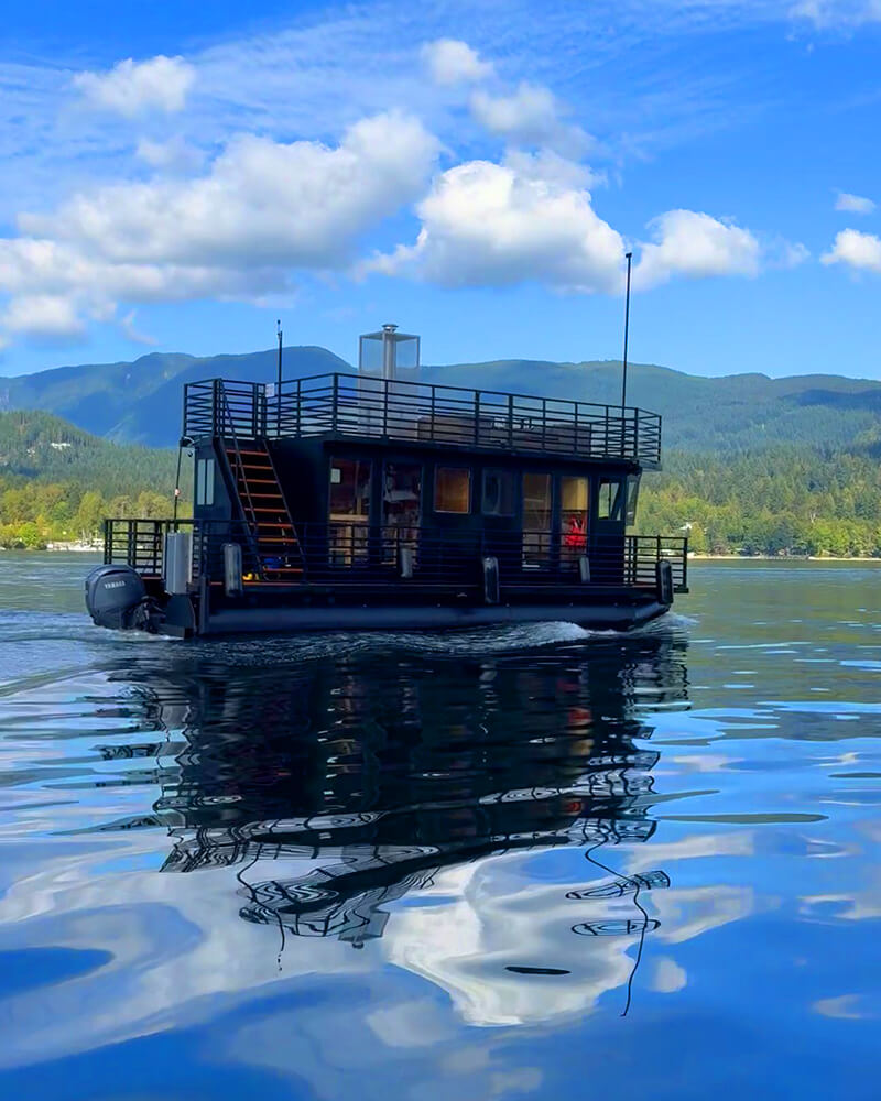 Exterior side view of the black 35-foot Hot Voyage sauna boat on the water.