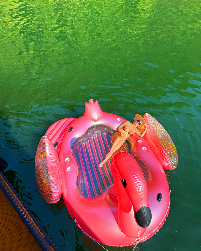 A pink flamingo floatie resting on the water next to the Hot Voyage sauna boat.