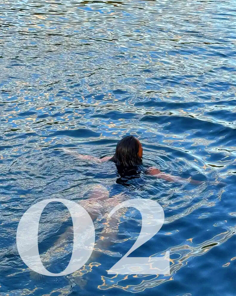 A woman swimming in the dark blue ocean waters of a fjord.