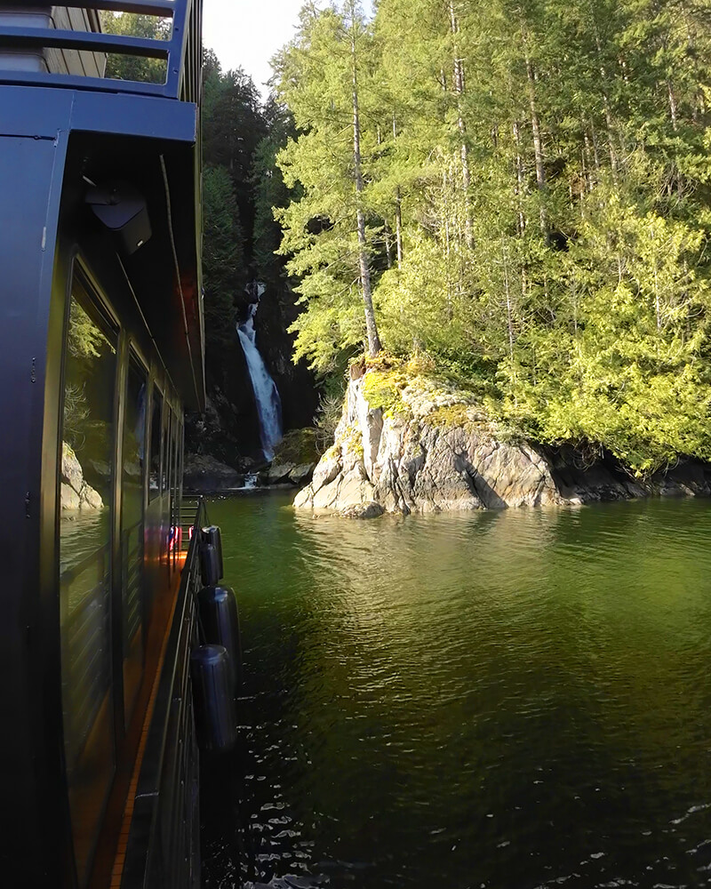 View of a waterfall from the wooden lower deck of the Hot Voyage sauna boat.