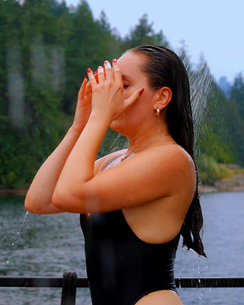 Woman wiping her face on the Hot Voyage sauna boat deck after a cold plunge.
