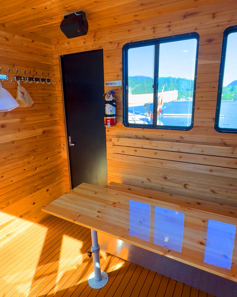 Cedar-paneled interior lounge of the Hot Voyage sauna boat with seating.